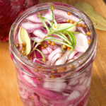 A close up over view of a jar of pickled red onions on a table.