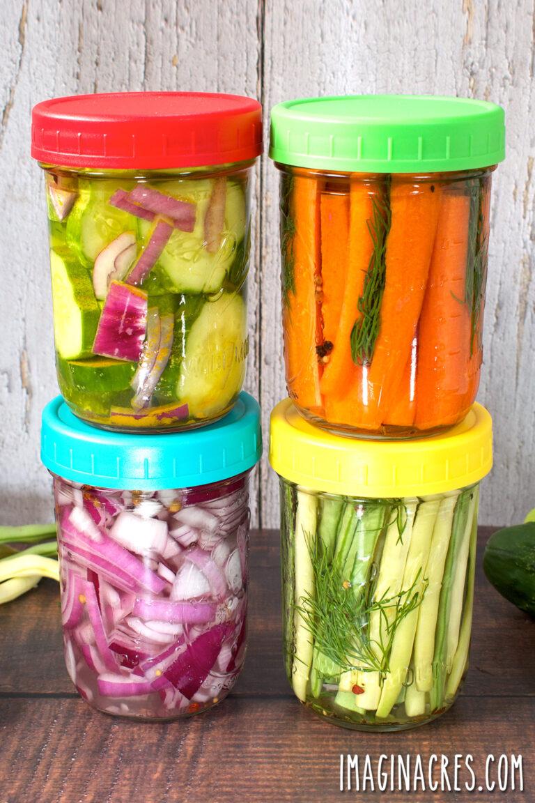 Four jars of refrigerator pickles stacked on a table.